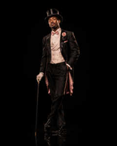 1920s Cabaret Emcee Chicago Vaudezilla 1920s cabaret emcee in a black tailcoat and top hat against a black background