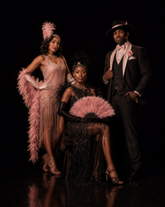 Cabaret Performers for Hire Chicago Vaudezilla Two glamorous showgirls and a tuxedoed cabaret host posed against a black background