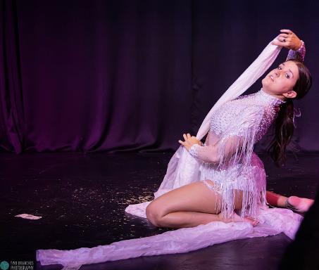 Emma Lucia | Chicago Aerial Specialty Performer Vaudezilla Emma Lucia performing on stage in a white fringed costume